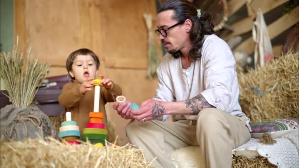 父亲和儿子在谷仓里玩五彩缤纷的生态木制玩具 靠近正方形草包 — 图库视频影像