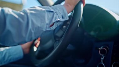 Gündüz araba kullanırken direksiyon simidini çeviren birinin yakın çekimi.