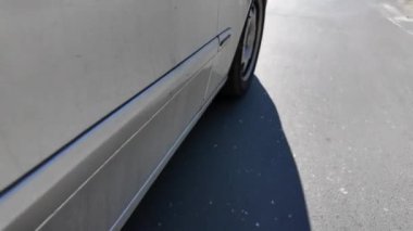 Yolun aşağısında gümüş renkli bir araba var.