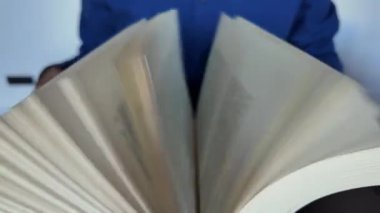 Büyük bir kitabı karıştıran bir adamın yakın çekimi.