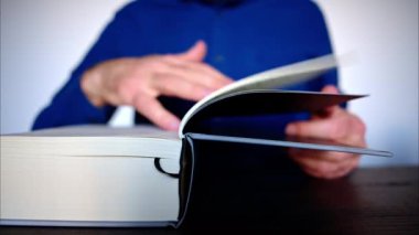 Büyük bir kitabı karıştıran bir adamın yakın çekimi.