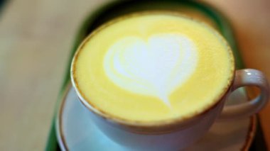Kalp tasarımlı sarı zerdeçal latte bardağını kapat.