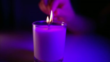 Mor yıldırımla kokulu bir mum yakan kişi