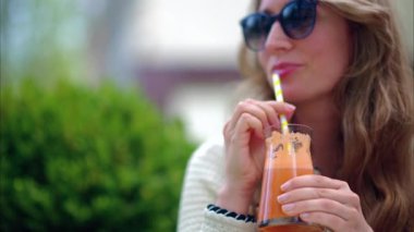 Dışarıdaki kafede portakal suyu içen bir kadın.