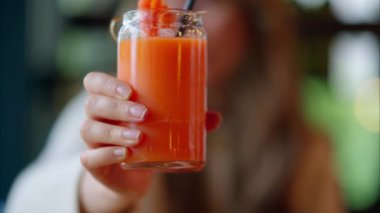 Restoranda havuç suyu içen bir kadın pipet kullanıyor.