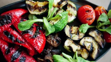 Siyah bir tabak ızgara biber, kiraz domates, kabak, patlıcan ve mantar.