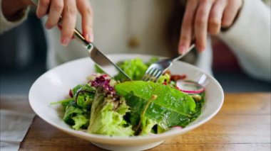Restoranda taze salata yiyen bir kadın.