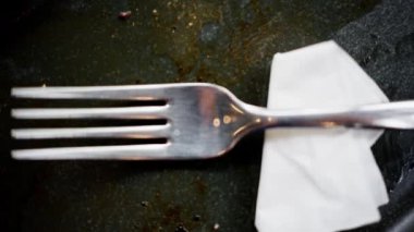 Çelik bir çatalı kağıt bir havluyla siyah bir tabakla kapat.