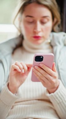 Bir kafede telefonunu karıştıran ceketli bir kadın.