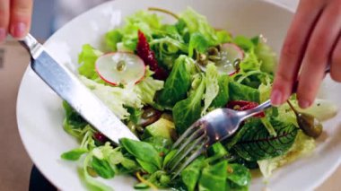 Restoranda taze salata yiyen bir kadın.