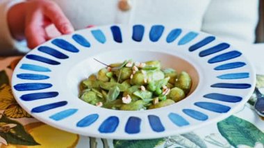 İtalyan restoranında soslu gnocchi yiyen bir kadın.