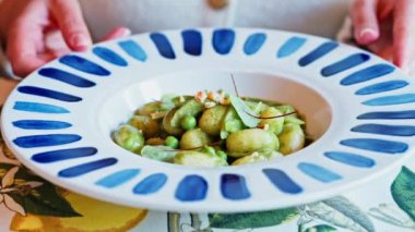 İtalyan restoranında soslu gnocchi yiyen bir kadın.