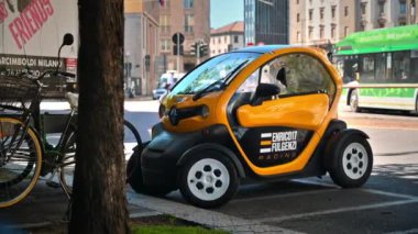 Milan, İtalya - 18 Nisan 2024: Küçük, bir kişi, bir motosikletin yanındaki otoparkta turuncu bir araba, sokakta