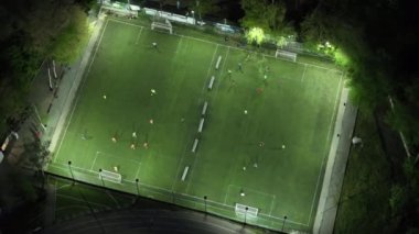 İnsanlar geceleri iki aydınlık stadyumda futbol oynuyorlar.