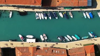 Burano Adası, Venedik, İtalya 'daki renkli evlerin yakınındaki bir kanaldaki teknelerin havadan görüntüsü.