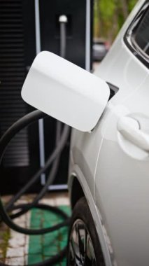 Elektrik santralinden şarj olan beyaz bir arabaya yaklaş. Dikey