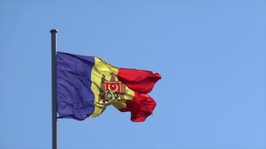 Moldova Cumhuriyeti bayrağı arka planda mavi bir gökyüzü ile sallanıyor, yavaş çekim