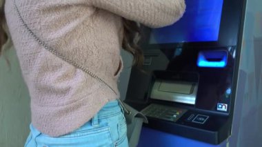 Kartı tanıtan ve ATM ekranına dokunan bir kadın.