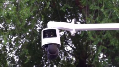 Siyah beyaz, arka planda ağaçlar olan bir güvenlik kamerası.