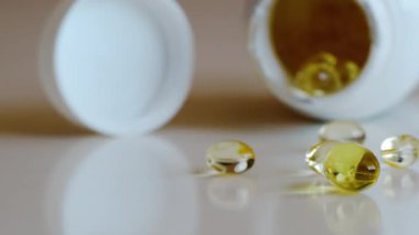 Balık yağı omega 3 takviyeleri beyaz arka planda bir paketleyiciden dökülüyor.