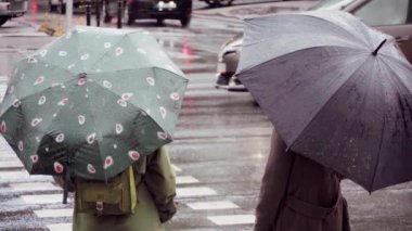 Yağmurda karşıdan karşıya geçmek için şemsiyeli insanlar bekliyor.