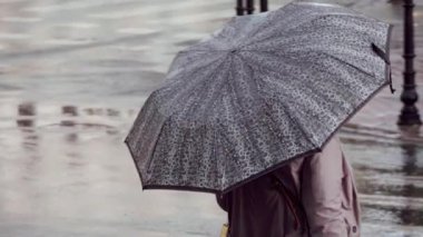 Yağmurda karşıdan karşıya geçmek için elinde şemsiyesi olan bir kadın bekliyor.