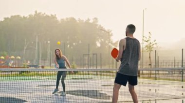 Bir adam ve bir kadın yağmurdan sonra top oynuyorlar.