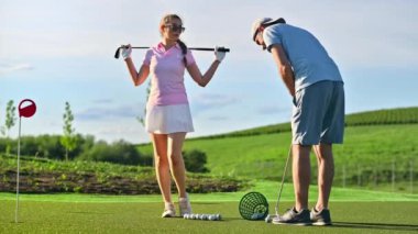 Güneşli bir günde golf oynayan bir adam ve bir kadın.