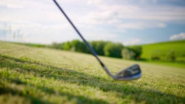 Güneşli bir günde çimlerin üzerinde ileri geri sallanan golf sopası.