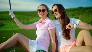 Golf sahasında duran iki kadın kovanın yanında taşakları dökülmüş.