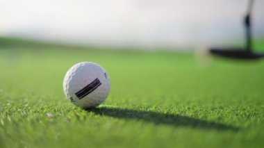 Sahada topa vuran bir golf sopasının yakınında.