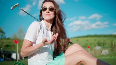 Golf topuyla oynayan bir kadın kovanın yanında duruyor.