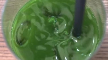 Bardakta siyah bir pipetle buzla çevrili yeşil bir meyve suyuna yaklaş.