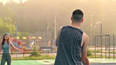 Bir adam ve bir kadın yağmurdan sonra güneşin doğuşunda pikbol oynuyorlar.