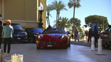 Monte Carlo, Monako - 8 Haziran 2024: Kırmızı Ferrari caddede yürüyor, yanında insanlar var.