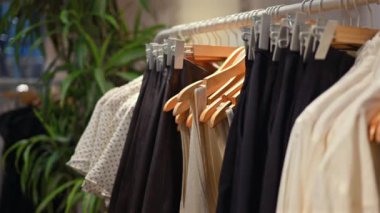 Siyah beyaz elbiseler bir mağazanın rafında duruyor.