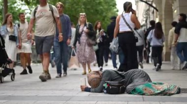 Paris, Fransa - 18 Haziran 2024: Sokakta evsiz bir kadının yanından geçen insanlar
