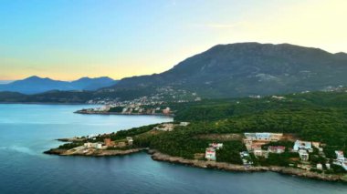 Adriyatik Denizi kıyısında, Karadağ 'ın arka planında dağlar bulunan binaların hava ve insansız hava aracı görüntüsü