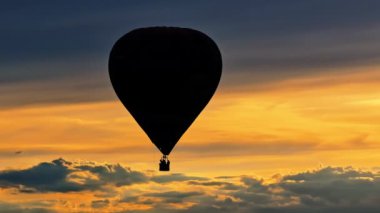 Gün batımında bulutların üzerinde uçan sıcak hava balonunun drone görüntüsü