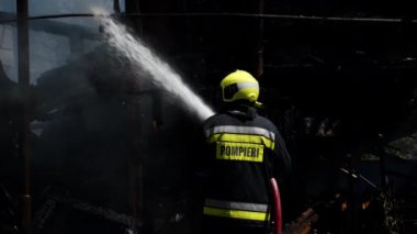 İtfaiyeci yangını söndürmeye çalışıyor.