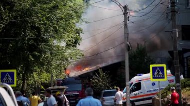 Chisinau, Moldova - 6 Temmuz 2024: Arka planda yangın yanan bir ambulans ve itfaiye aracının etrafında hareket eden insanlar