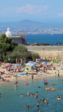 Antibes, Fransa - 20 Temmuz 2024: İnsanlar denizde yüzüyor ve plajda dinleniyorlar. Dikey