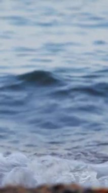 Sahilde dalgalar kıyıya vuruyor. Dikey