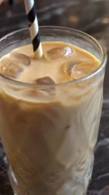 Pipetle çevrilmiş buzlu lattenin yakın çekimi. Dikey