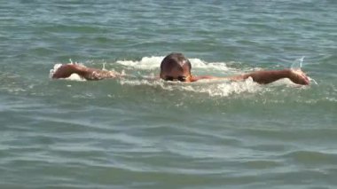 Güneşli bir günde denizde yüzen adam