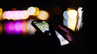 Geceleri sahilde telefonunu kaydıran bir kadın.