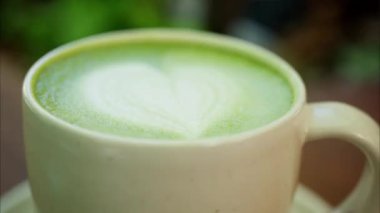 Matcha latte 'nin üzerindeki bir kalp latte sanatını kapat.