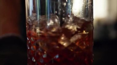 Barmen bardakta buzla alkolü karıştırıyor.