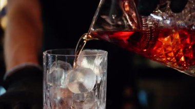Barmen buzlu bardakta alkolü süzüyor.