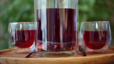 Terasta bir masada iki bardak meyve çaydanlığı ile bir infuser çaydanlığını kapat